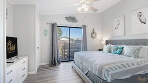 A bedroom with a bed, a television, and a view of the outside.