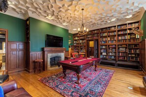 A library with a billiards table, bookshelves, and a fireplace. - The Castle at Valle Crucis (Banner Elk)