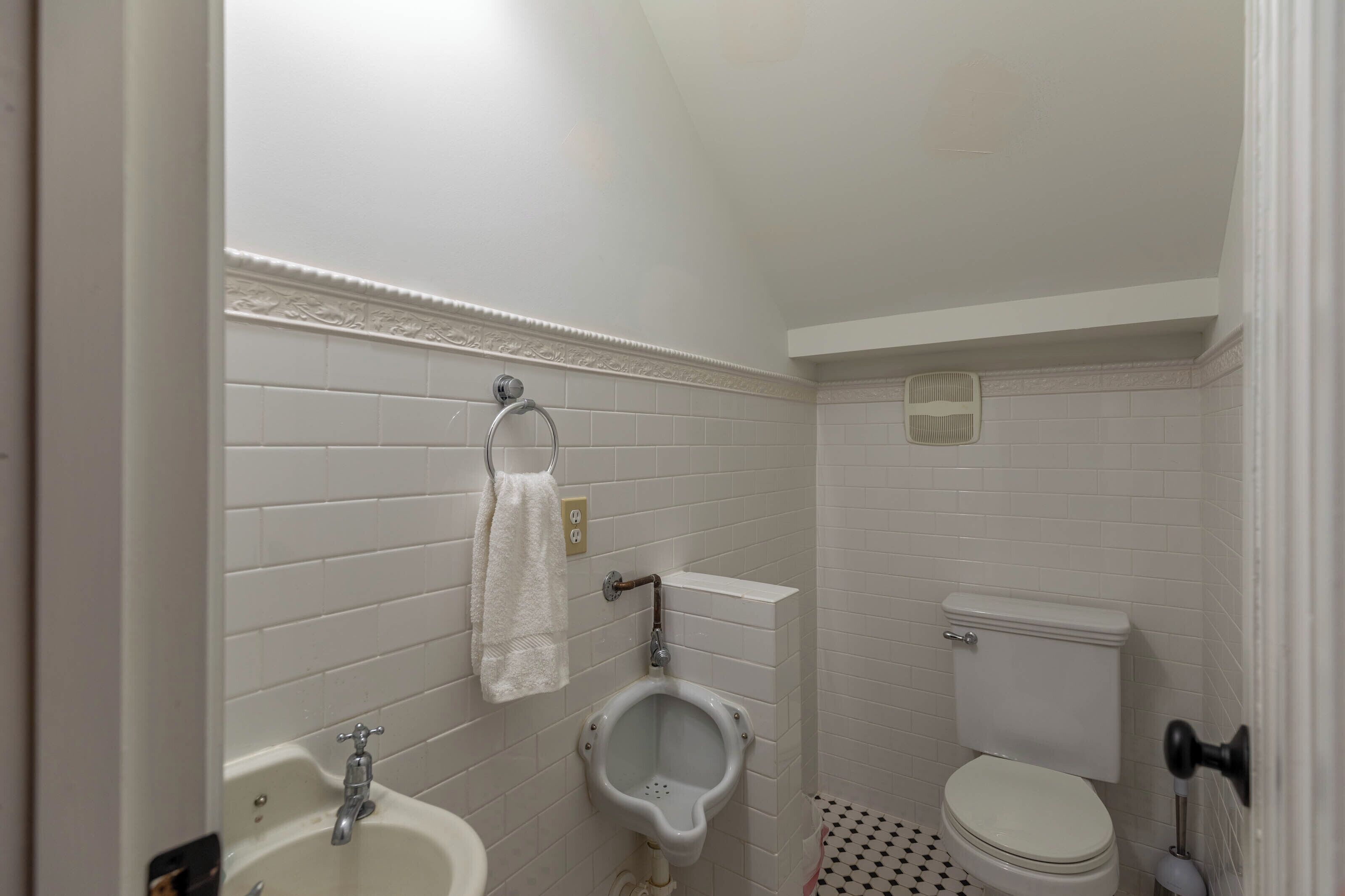 A small, clean bathroom with a toilet, urinal, and sink.