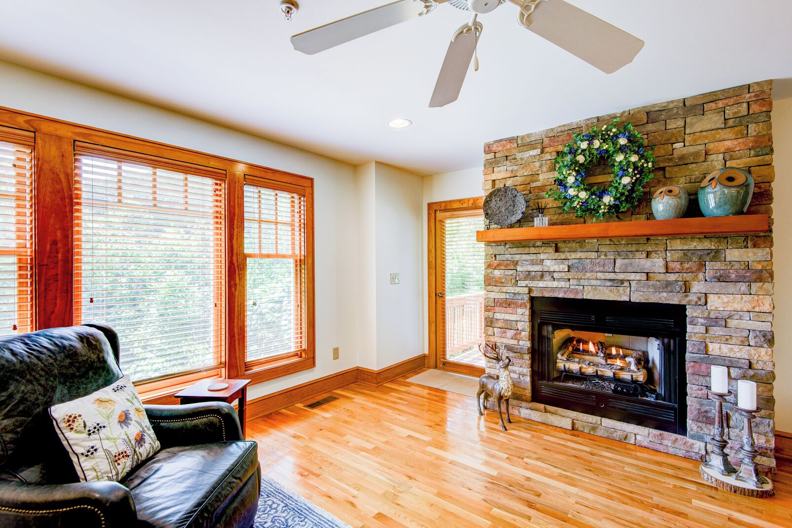 A spacious living room with a fireplace, wooden flooring, and large windows.