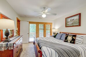 Un dormitorio con cama, cómoda, ventilador de techo y puerta con vista al exterior.