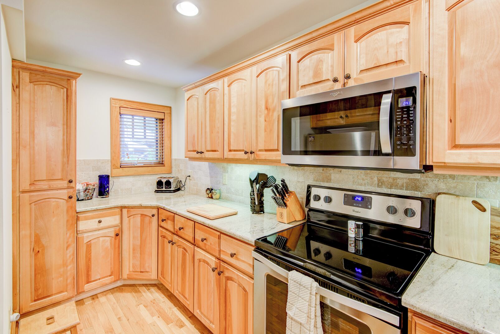 A kitchen with wooden cabinets, a microwave, an oven, and a toaster.