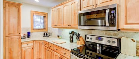 A kitchen with wooden cabinets, a microwave, an oven, and a toaster.