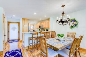 Une cuisine moderne avec des meubles en bois, un îlot central et un coin repas agrémenté d’un lustre et de décorations florales.