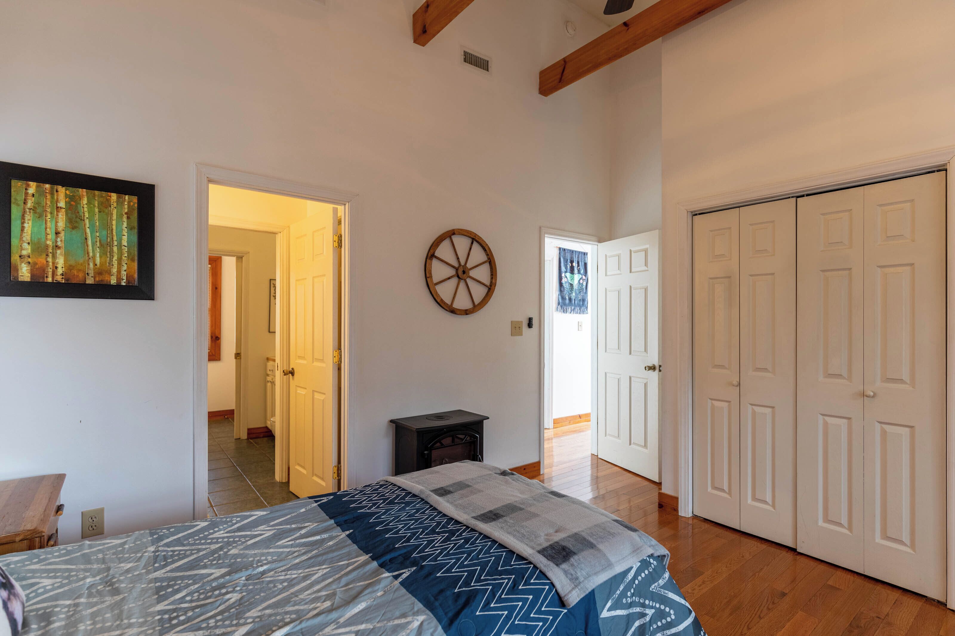 A bedroom with a bed, a small table, a wall-mounted wheel, and a wardrobe.