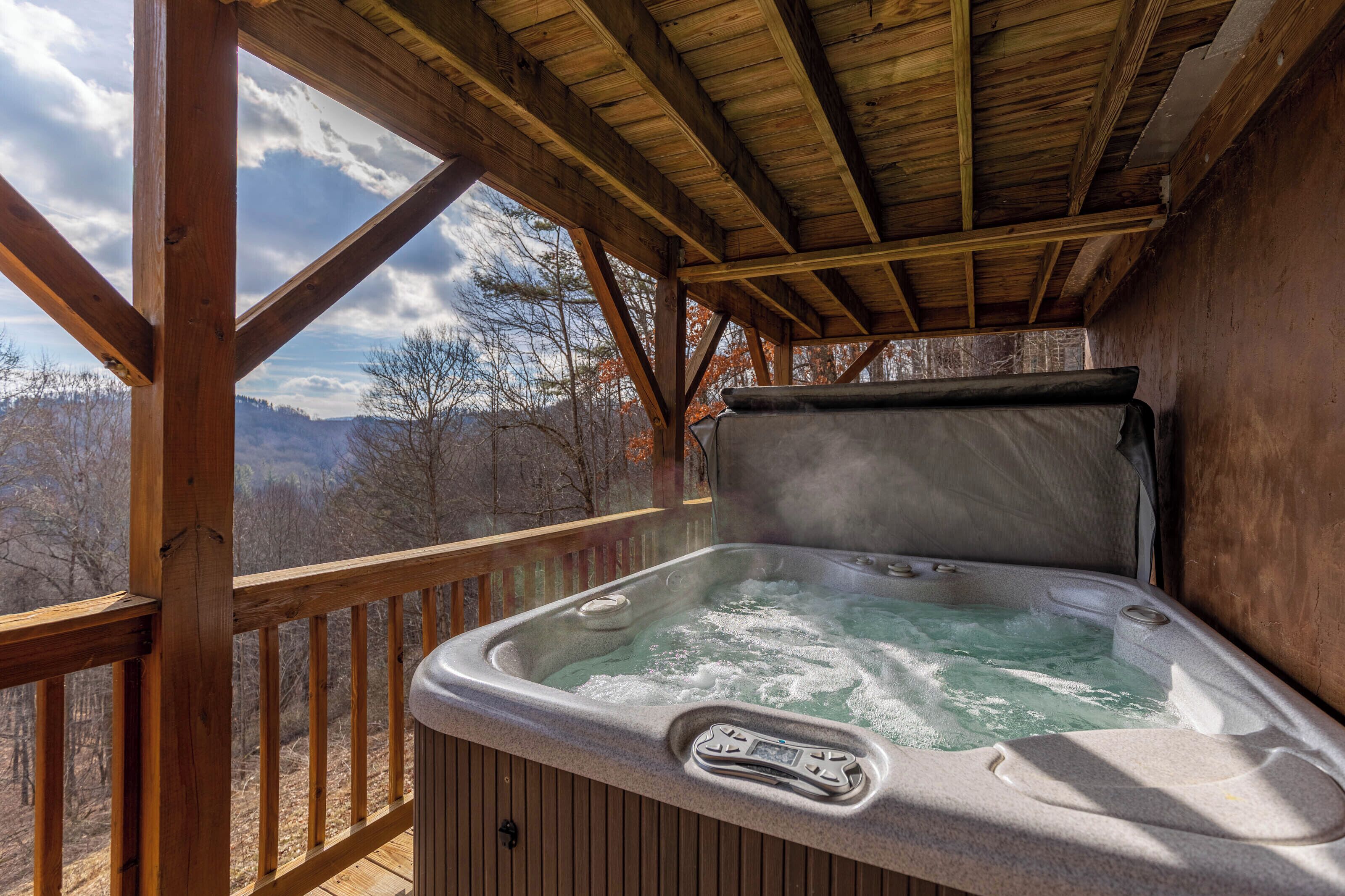 A hot tub with a wooden deck and a view of the mountains.