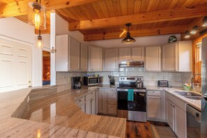 Una cocina moderna con armarios blancos, electrodomésticos de acero inoxidable y techo de madera.