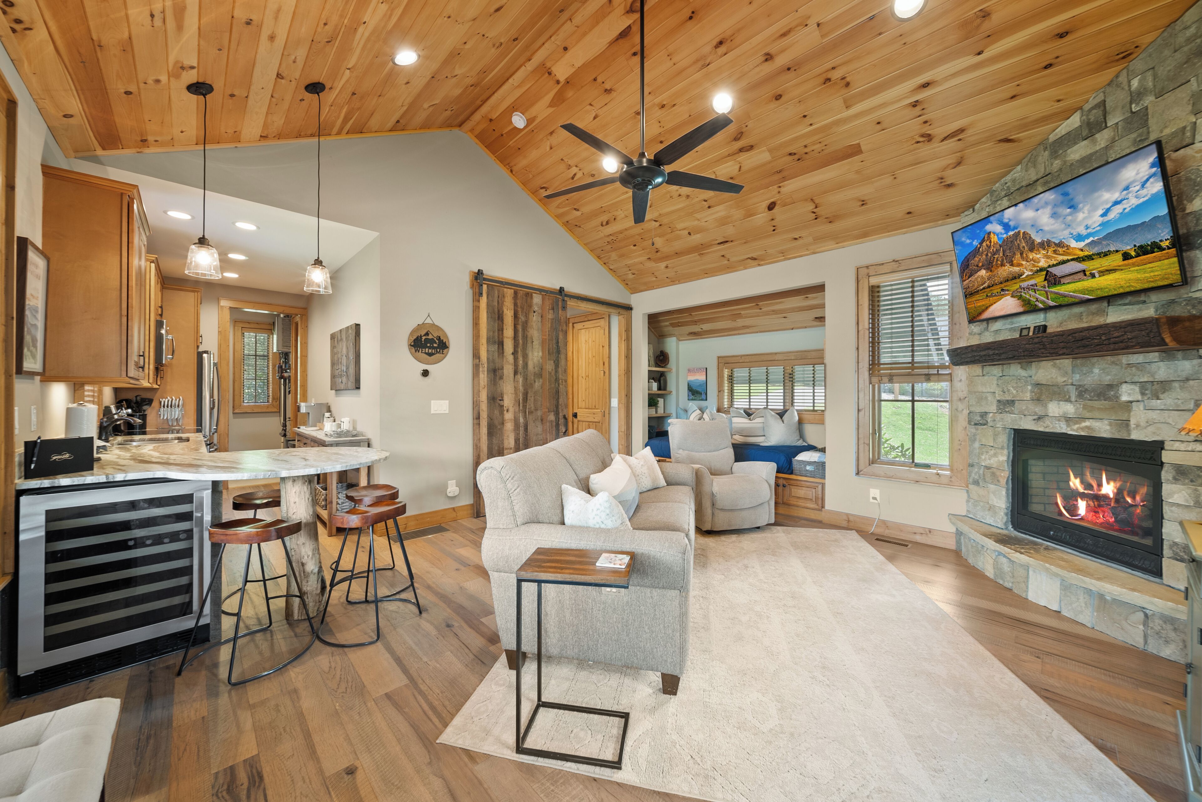 A spacious living area with a fireplace, a dining area with bar stools, and a kitchen with wooden cabinets.