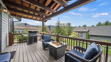 A covered deck with wicker furniture, a grill, and a fire pit.