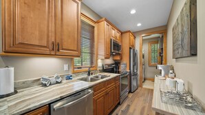 A modern kitchen with wooden cabinets, stainless steel appliances, and a marble countertop. - River Rock (Banner Elk)