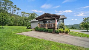 A two-story house with a porch, a flag, and a driveway leading to the entrance. - River Rock (Banner Elk)