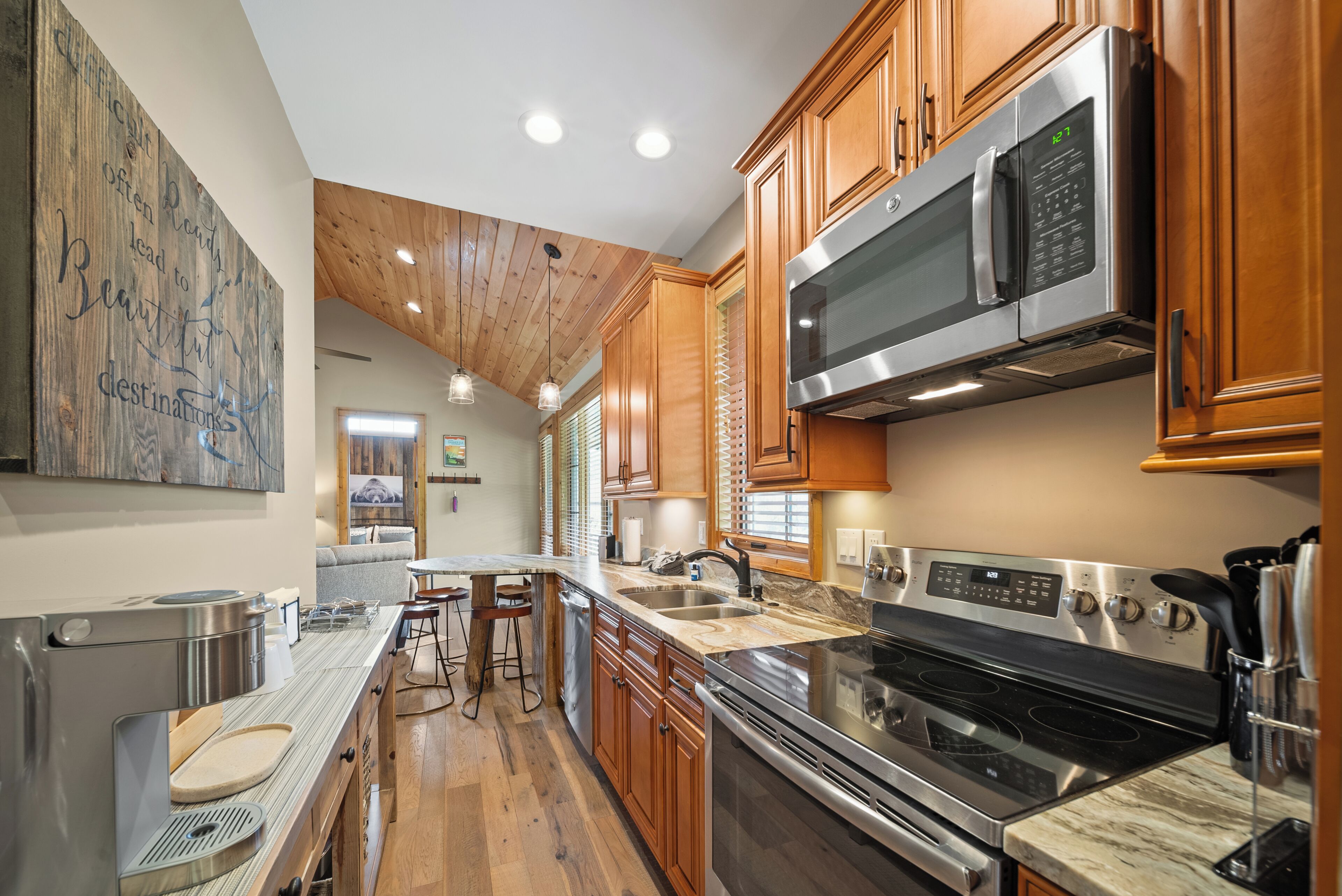 A modern kitchen with wooden cabinets, stainless steel appliances, and a marble countertop.
