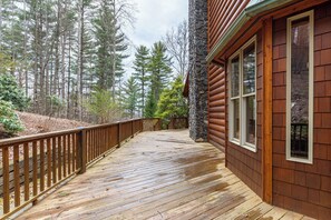 Eine Holzterrasse mit einer Steinmauer und Fenstern, umgeben von einem Wald.