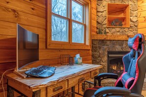A wooden cabin interior with a desk, computer, and gaming chair. - The Forge (Lansing)