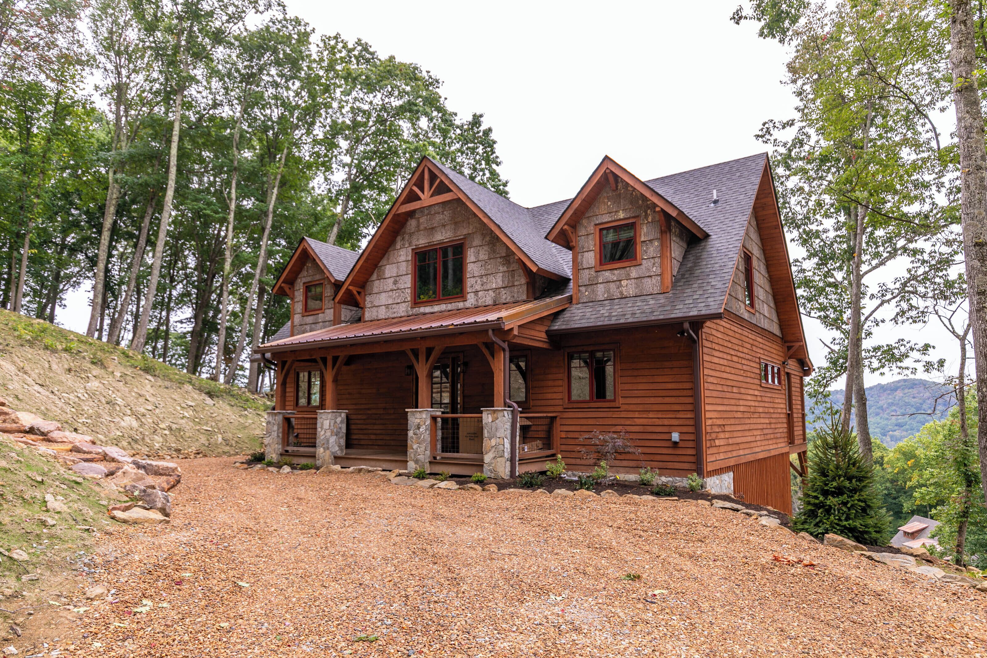 A log cabin with a stone foundation, multiple windows, and a porch.