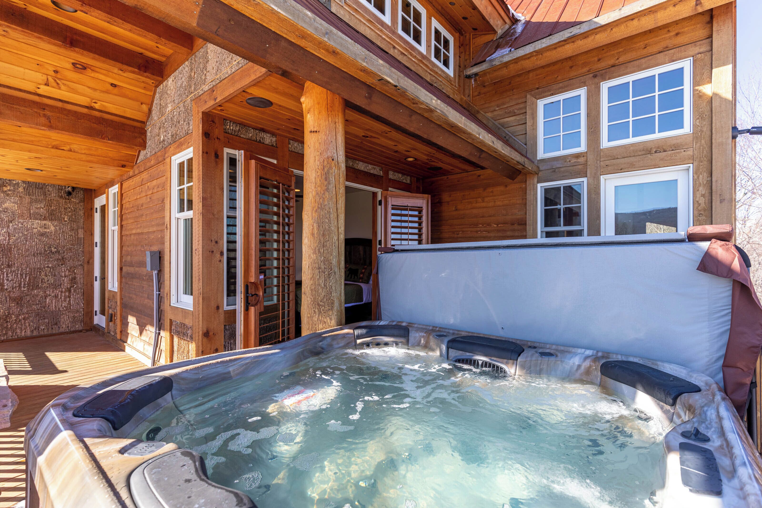 A wooden cabin with a hot tub and a covered deck area.