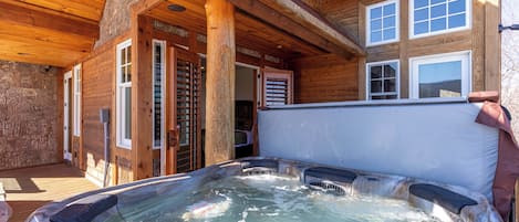 Una cabaña de madera con hidromasaje y una terraza cubierta.