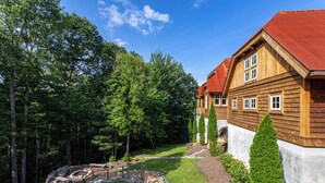 A wooden house with a red roof, surrounded by a well-maintained garden and trees. - Wild Turkey Inn at Eagles Nest (Banner Elk)
