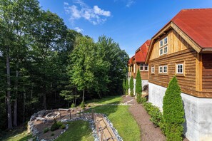 Ein Holzhaus mit rotem Dach, umgeben von einem gepflegten Garten und Bäumen.