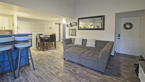 A living room with a gray sectional sofa, a kitchen area with white cabinets, and a dining table with chairs. - 7035 Park City #3R (Park City)