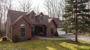 A two-story house with a front porch, a garage, and a well-maintained lawn. - White Tail Cottage (Banner Elk)
