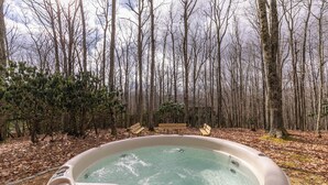A hot tub surrounded by a forest with benches. - White Tail Cottage (Banner Elk)