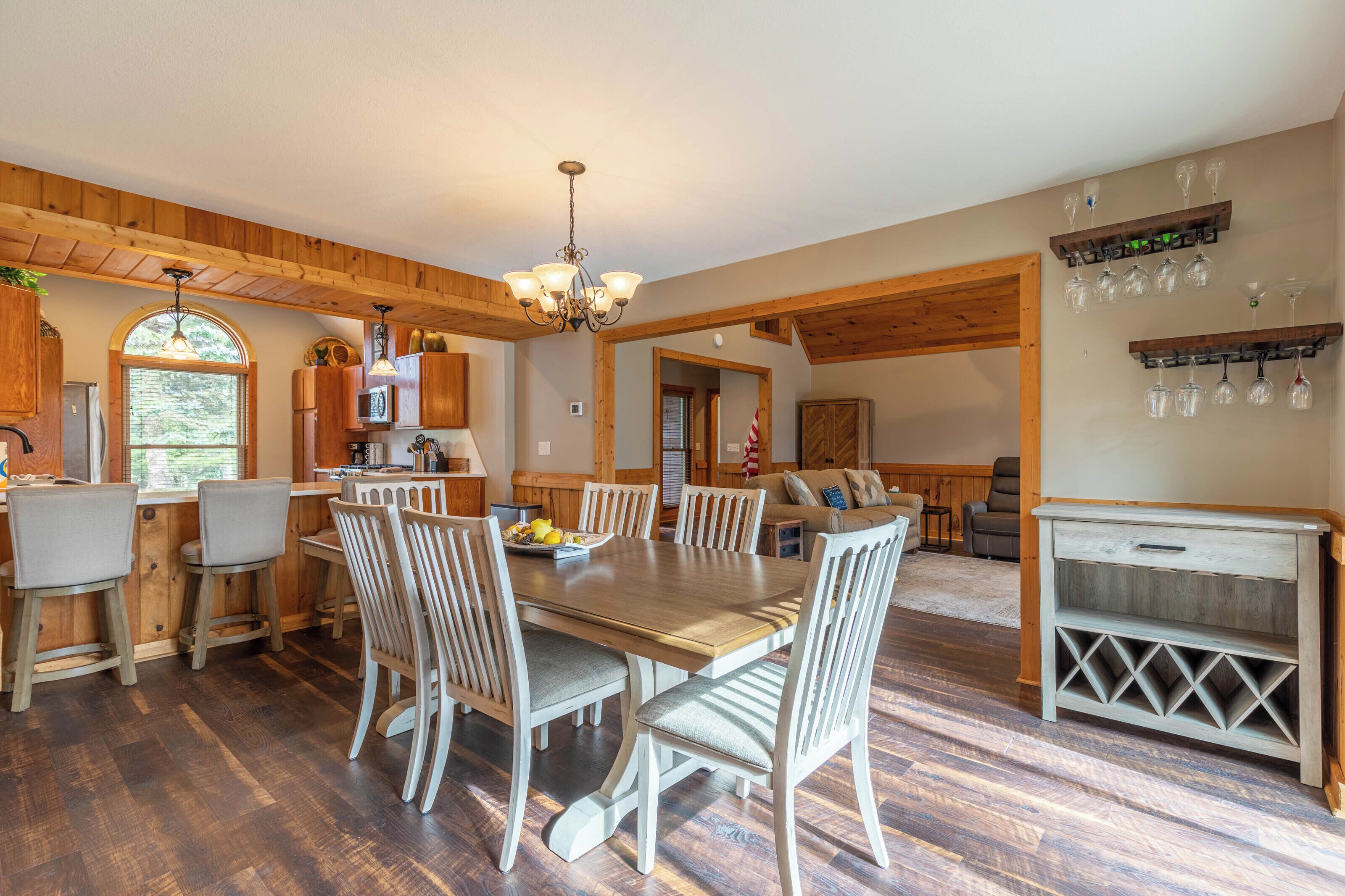 A spacious kitchen with wooden beams, a dining area with a large table and chairs, and a living area with a sofa and TV.