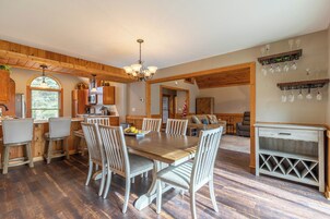 A spacious kitchen with wooden beams, a dining area with a large table and chairs, and a living area with a sofa and TV.