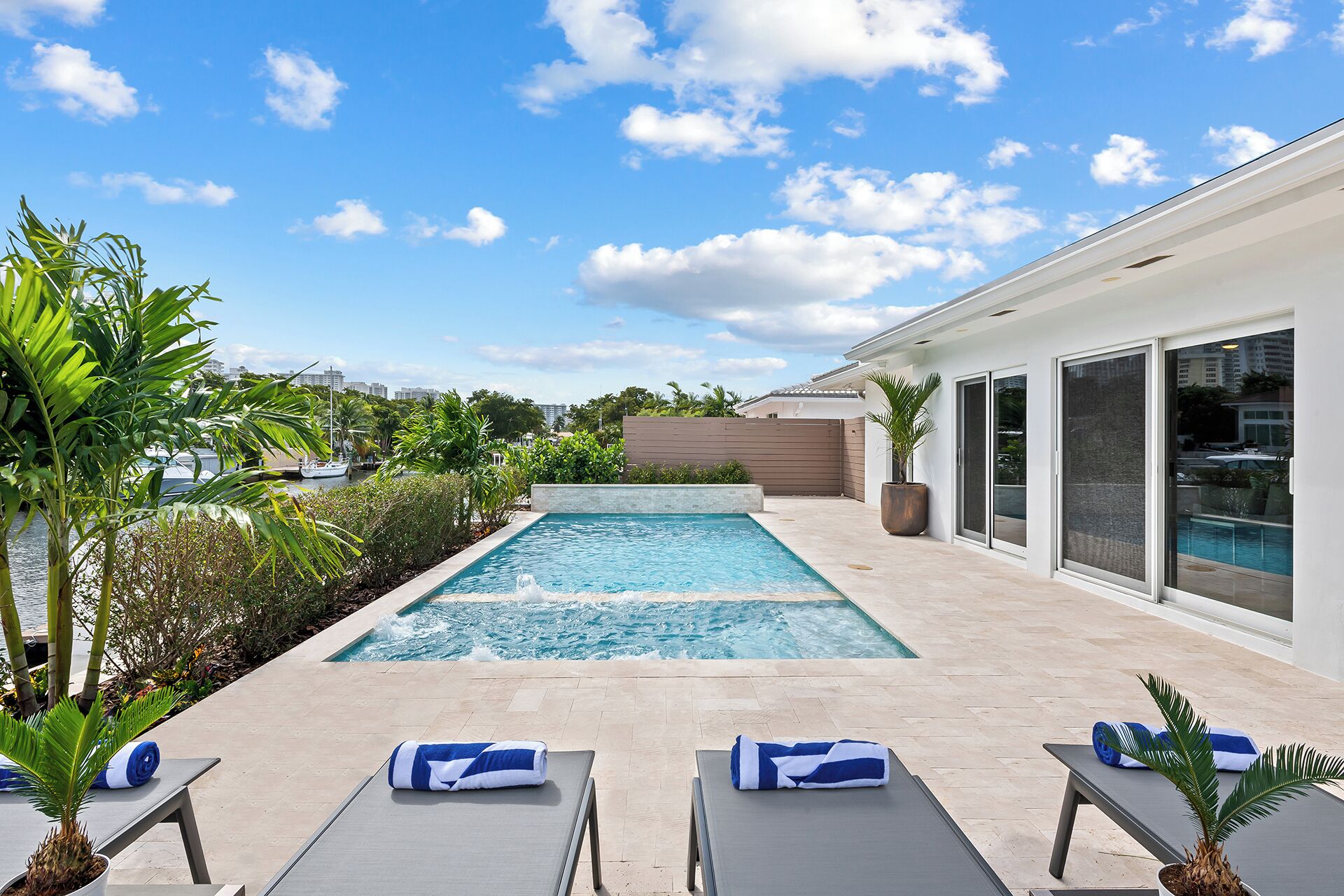 Área moderna de piscina ao ar livre com espreguiçadeiras e vista para o horizonte da cidade.