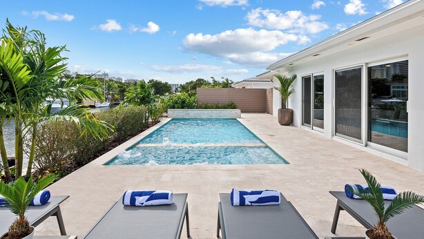 A modern outdoor pool area with lounge chairs and a view of the city skyline. - Beach Bunny (Fort Lauderdale)