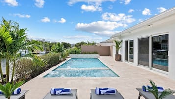 Ărea moderna de piscina ao ar livre com espreguiçadeiras e vista para o horizonte da cidade.