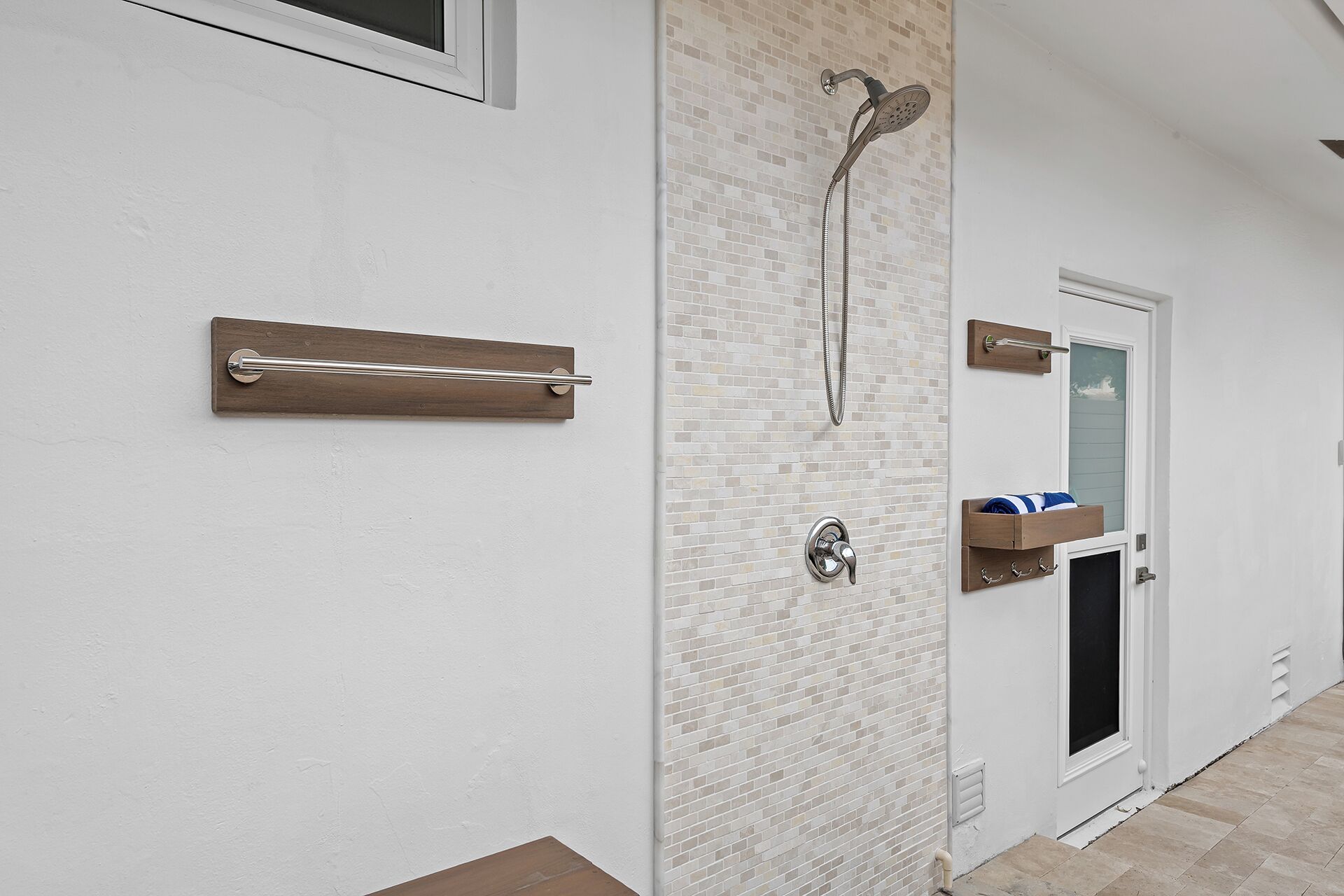 A bathroom with a shower, a towel rack, and a towel shelf.