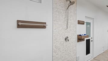 Casa de banho com chuveiro, porta-toalhas e prateleira para toalhas.