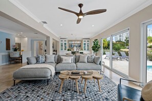 A modern living room with a large gray sectional sofa, a wooden coffee table, and a ceiling fan. - Beach Bunny (Fort Lauderdale)
