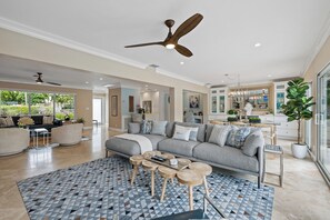 A spacious living room with a grey sofa, wooden coffee tables, and a patterned rug. - Beach Bunny (Fort Lauderdale)