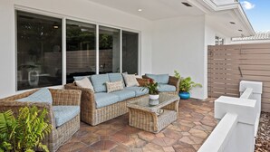 An outdoor patio with wicker furniture, a glass coffee table, and potted plants. - Beach Bunny (Fort Lauderdale)