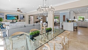 A spacious living area with a glass dining table, white wicker chairs, and a grey sofa. - Beach Bunny (Fort Lauderdale)