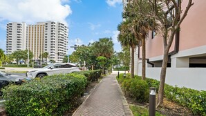 A paved walkway flanked by greenery and modern buildings. - Beach Bunny (Fort Lauderdale)