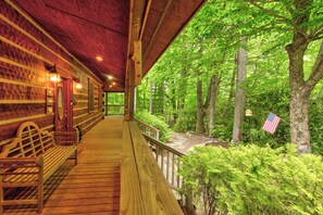 A wooden cabin with a porch, benches, and a view of a forested area. - Hebron Falls Cabin (Boone)
