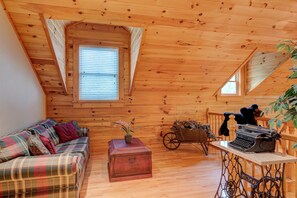 Ein gemütliches Blockhaus-Interieur mit einem karierten Sofa, einer Vintage-Schreibmaschine und einem Holzwagen.
