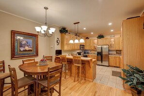 Eine moderne Küche mit Holzausbau, einem Edelstahlkühlschrank und einem Essbereich mit Holztisch und Stühlen.