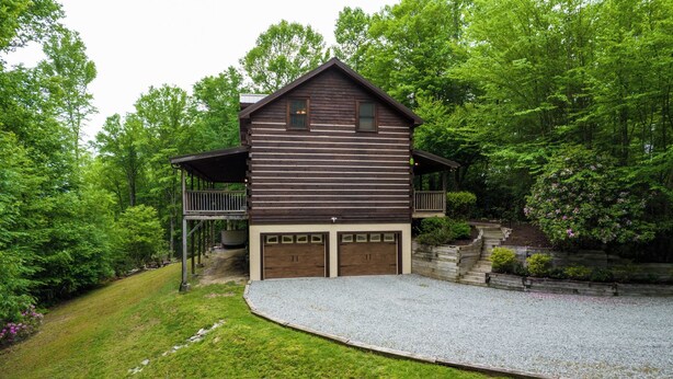 A two-story log cabin with a covered porch and a gravel driveway. - Hebron Falls Cabin (Boone)