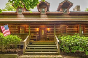 Une cabane en bois avec une véranda, des marches et un drapeau américain.