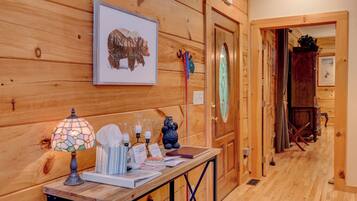 A wooden interior with a table displaying a bear painting, a stained glass lamp, and various items.
