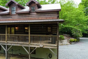 Eine Holzhütte mit Balkon, überdachter Veranda und einem Schotterweg.