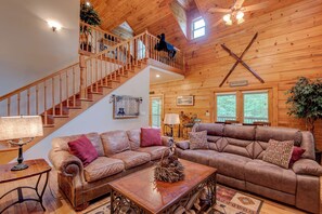 Un salon spacieux avec un escalier en bois, des canapés en cuir et une décoration rustique.