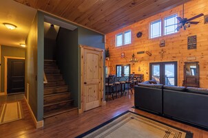 A wooden interior with a staircase, a dining area, and a seating area.