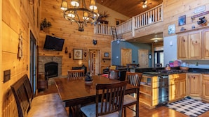 A cozy cabin interior with a dining area, kitchen, and a loft bedroom. - Porridge Pot (Marion)
