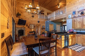 Un intérieur de chalet chaleureux comprenant un coin repas, une cuisine et une chambre à coucher située en mezzanine.