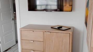Une pièce avec un meuble en bois, un téléviseur fixé au mur et un tapis à motifs sur le sol.